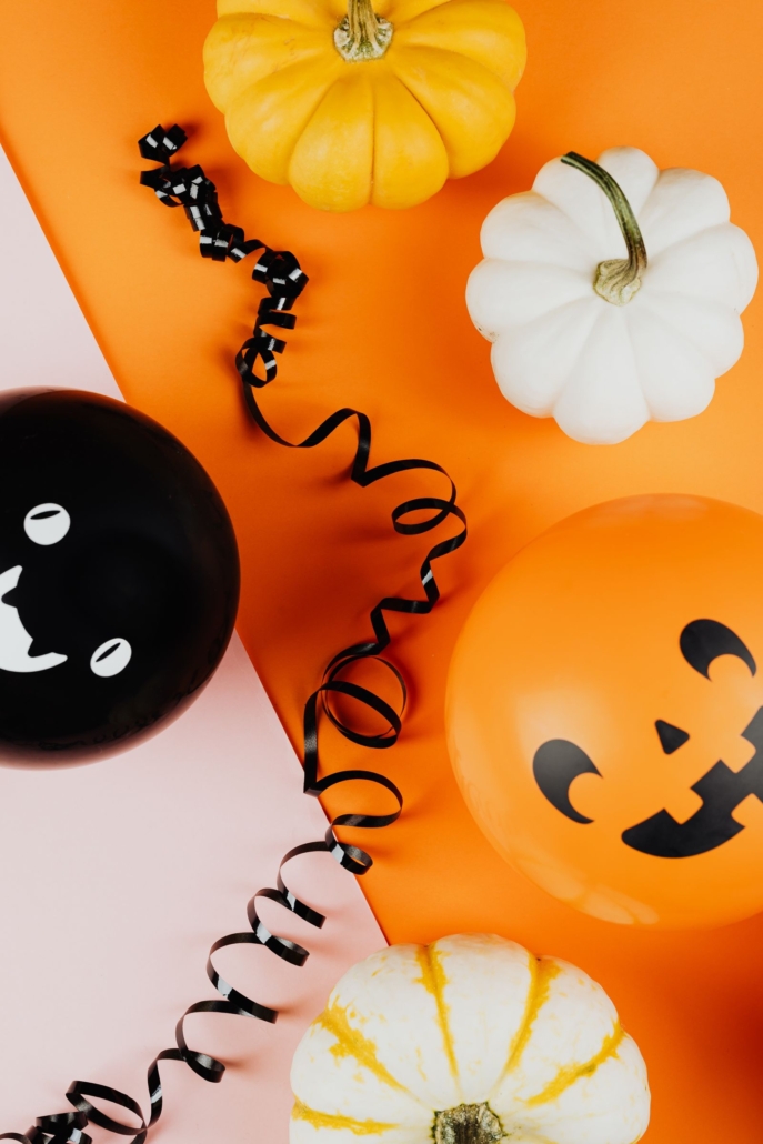 Globos de Halloween naranja y negro con calabazas sobre fondo rosa y naranja